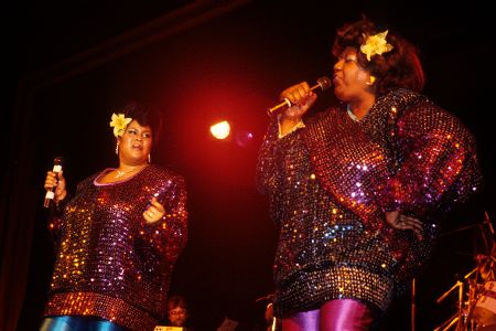 Zwei schwarze Frauen auf einer Bühne mit Mikrofon in der Hand