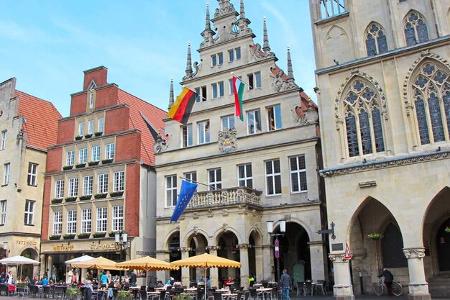 Am Prinzipalmarkt von Münster steht das beflaggte Stadtweinhaus von 1615, rechts daneben das Rathaus