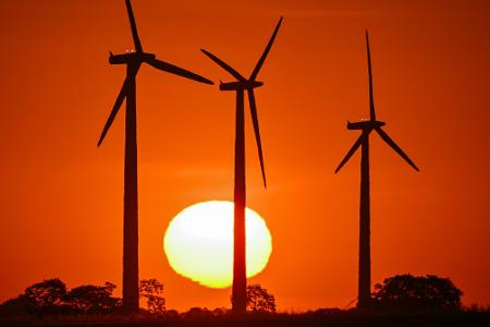 Am frühen Morgen leuchtet der Sonnenaufgang im Landkreis Märkisch-Oderland im Osten von Brandenburg. Ein guter Tag für Solaranlagen, aber ob die Windenergieanlagen heute zum Einsatz kommen werden?