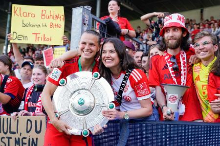 Jetzt ist es offiziell: Die Fußballerinnen des FC Bayern München sind nach dem letzten Bundesliga-Spieltag im baden-württembergischen Sinsheim Meister. Stürmerin Klara Bühl (l) freut sich mit der Meisterschale in den Händen vor der Fankurve.