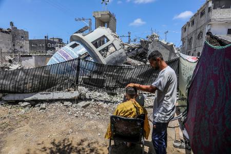 Ein Stückchen Normalität: Ein Friseur arbeitet neben einer zerstörten Moschee nach einem israelischen Luftangriff auf die Stadt Deir al-Balah im Gaza-Streifen.