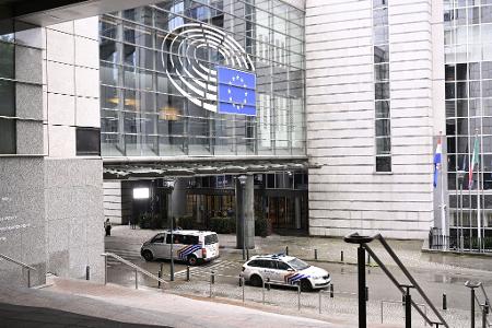 Poilzeiautos vor dem EU-Parlament in Brüssel: Im Zusammenhang mit mutmaßlicher russischer Einflussnahme sind die Wohnung und die Büros eines Mitarbeiters des Europäischen Parlaments durchsucht worden.