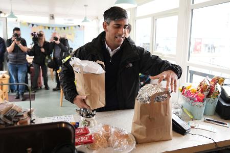 Der britische Premierminister Rishi Sunak kauft ein Frühstück für die mitreisenden Journalisten, als er zu einer Wahlkampfveranstaltung der Konservativen im Südwesten Englands an einem Bahnhof ankommt.
