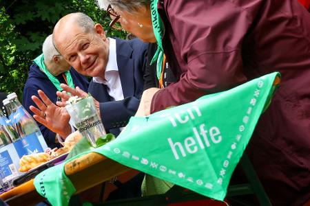 Zeit für ein Pläuschen: Bundeskanzler Olaf Scholz unterhält sich auf dem Katholikentag in Erfurt mit freiwilligen Helfern.