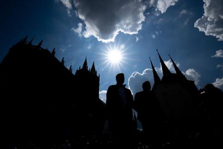 Besucher des Deutschen Katholikentages stehen im Gegenlicht der Sonne vor der Silhouette des Erfurter Doms. Das Christentreffen geht noch bis Sonntag; rund 500 Veranstaltungen finden insgesamt statt.