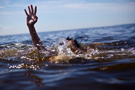 Mensch im Wasser hebt hilfesuchend seine Hand