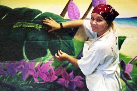 Frau mit Kopftuch steht vor bemalter Wand