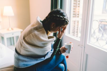 frau krank auf bett sitzend