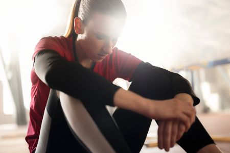 Sportlerin sitzt frustriert auf dem Boden