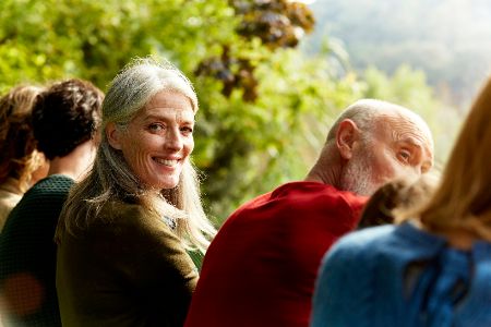 seniorin sitzt mit anderen draußen