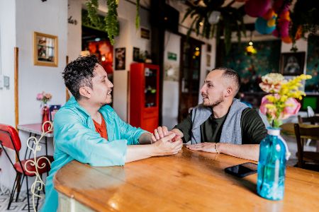 Zwei Männer halten im Restaurant Händchen