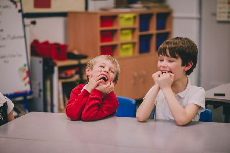 Zwei Schulkinder sitzen am Tisch und freuen sich