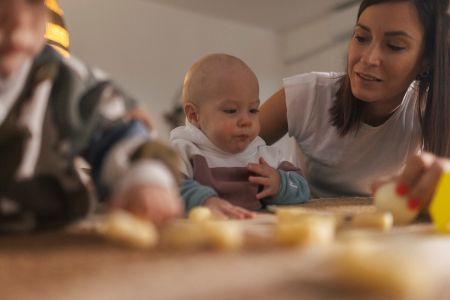 Mutter sitzt mit Baby am Tisch zum Füttern