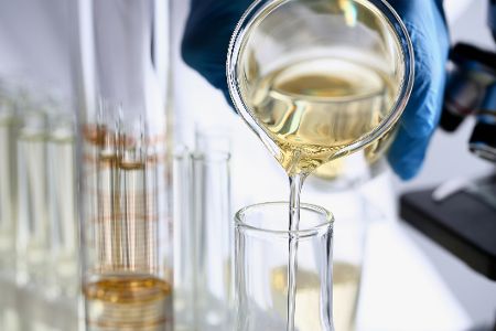 Gelbe, ölartige Flüssigkeit in einem Glas im Labor