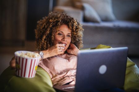 frau sieht sich was im laptop an und isst popcorn