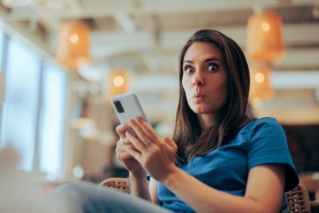 frau mit handy ist überrascht