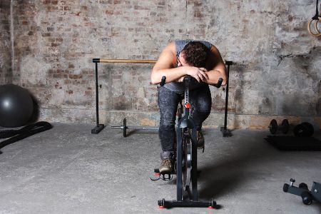 Mann schläft auf fitness bike