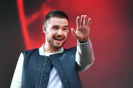 Liam Payne winkt Menschen von einer Bühne aus zhu.
