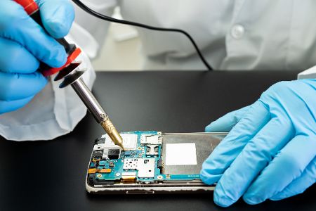 Techniker repariert das Innere des Mobiltelefons durch Lötkolben. Integrierter Schaltkreis. das Konzept von Daten, Hardware, Technologie