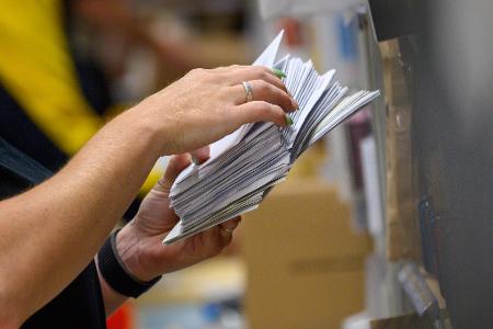 Eine Mitarbeiter der Deutschen Post sortiert in einem Zustellstützpunkt der Post Briefe.