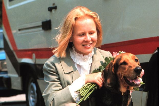 Mädchen sitzt in der Hocke und streichelt Hund
