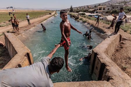 Das Foto des dpa-Fotografen Anas Alkharboutli zeigt syrische Jugendliche bei einer Abkühlung von der Hitze. 