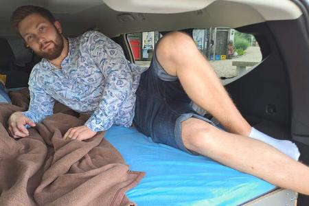 Junger Mann liegt im Heck des Dacia Jogger.