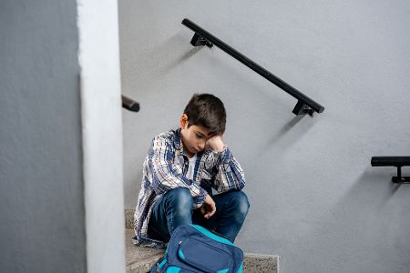 Junge sitzt allein auf einer Treppe