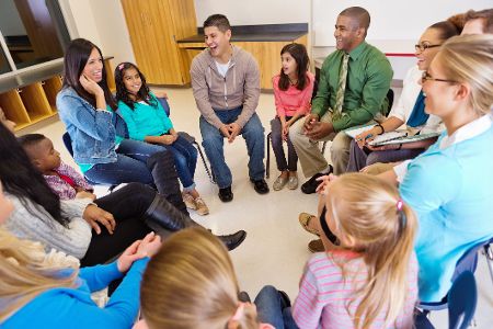 Schülerinnen und Schüler sitzen im Stuhlkreis mit einem Lehrer