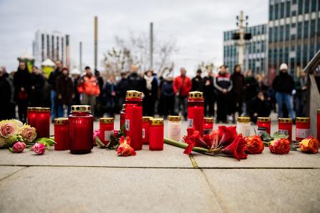 Menschen zünden Kerzen an und legen Blumen nieder.