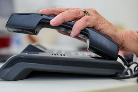 Eine Frau nimmt einen Telefonhörer in die Hand.