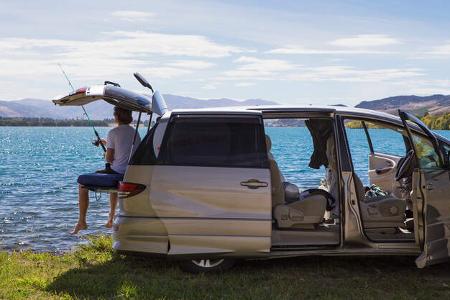 Carcamper steht am See und Mann angelt
