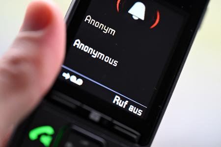 ILLUSTRATION - Ein Mann hält ein Festnetz-Telefon, auf dem ein anonymer Anruf eingeht (gestellte Szene). 