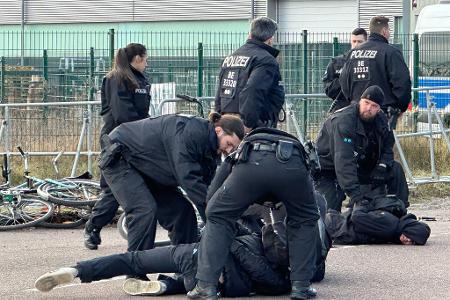 Polizisten halten Demonstranten am Boden fest. Sie hatten zuvor versucht mit Fahrrädern Richtung Veranstaltungshalle vorzudringen.