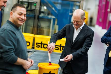 Kanzler Scholz macht beim Baustoffhersteller Sto eine Farbenprobe.