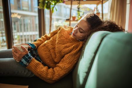 Erschöpfte Frau liegt auf Sofa