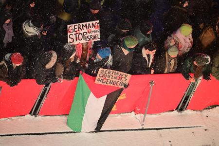 Zuschauer mit propalästinensischen Schildern am Rand des Teppichs.