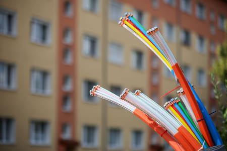 Erst mal angeschlossen, bieten sie Highspeed-Internet: Glasfaserkabel, die aus dem Sockel eines Schaltschranks herausragen.