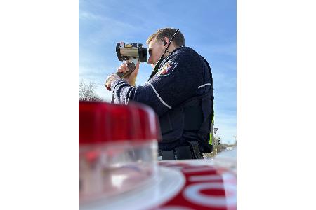 Ein Polizist misst die Geschwindigkeit von Autofahrern mit einem Lasermessgerät. Ein Polizist misst die Geschwindigkeit von Autofahrern mit einem Lasermessgerät.