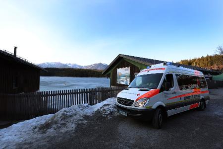Ein Einsatzfahrzeug des Roten Kreuzes steht am Ufer des Eibsees, nahe der Stelle an der am Nachmittag mehrere Menschen im Eis eingebrochen waren.