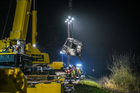 Mit einem großen Kran und unter Flutlicht werden Trümmerteile geborgen. 