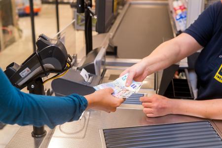 In einem Supermarkt hebt eine Kundin beim Bezahlen auch gleich Bargeld ab.