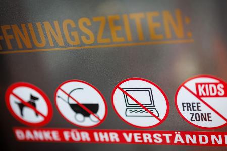 An einer Scheibe der Café-Bar 8tto Grammi weist ein Schild auf das Verbot von Laptops hin - wie auch auf das Verbot für Hunde, Kinderwägen und auf eine kinderfreie Zone. 
