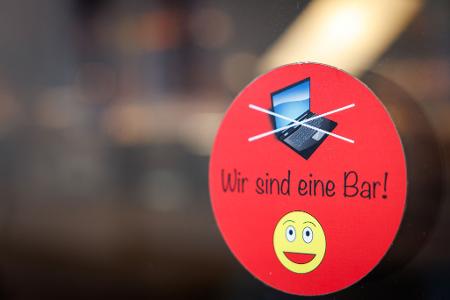 An einer Scheibe der Café-Bar 8tto Grammi in Bayreuth weist ein Schild auf das Verbot von Laptops hin.