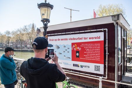 Menschen fotografieren ein Schild mit niederländischer Schrift an einem Fluss