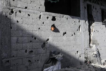Ein palästinensisches Kind schaut aus einem Loch in einem Gebäude in Chan Junis, das durch einen israelischen Luftangriff beschädigt wurde
