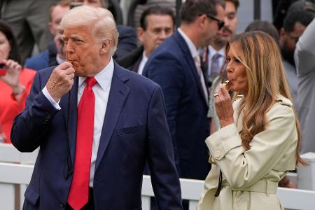 Präsident Donald Trump und Melania Trump blasen während des White House Easter Egg Roll in Trillerpfeifen.