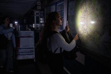 Eine Frau behilft sich mit der Taschenlampe ihres Handys, um den Plan des Madrider U-Bahn-Netzes anschauen zu können.
