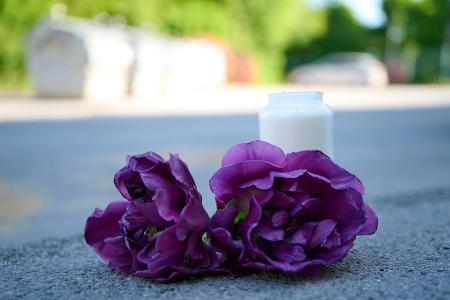 Blumen und eine Kerze liegen auf einem Schotterplatz vor dem Eingang zum Spielplatz, auf dem in der Nacht ein 17-Jähriger einen 14-Jährigen erstochen haben soll. Blumen und eine Kerze liegen auf einem Schotterplatz vor dem Eingang zum Spielplatz, auf dem in der Nacht ein 17-Jähriger einen 14-Jährigen erstochen haben soll.