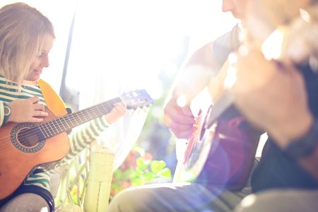 Menschen spielen im Sonnenschein draußen Gitarre